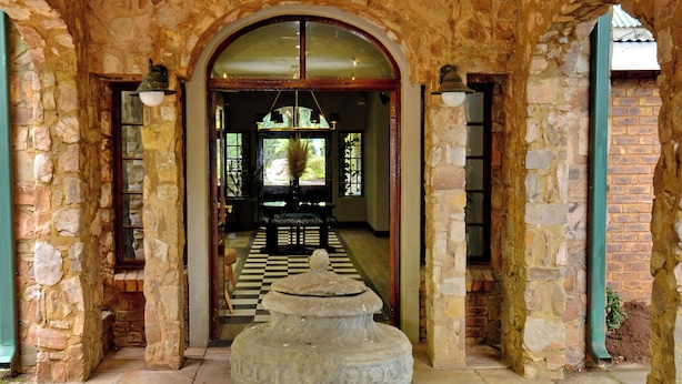 Un patio con paredes de piedra, una fuente central, puertas arqueadas e iluminación colgante.