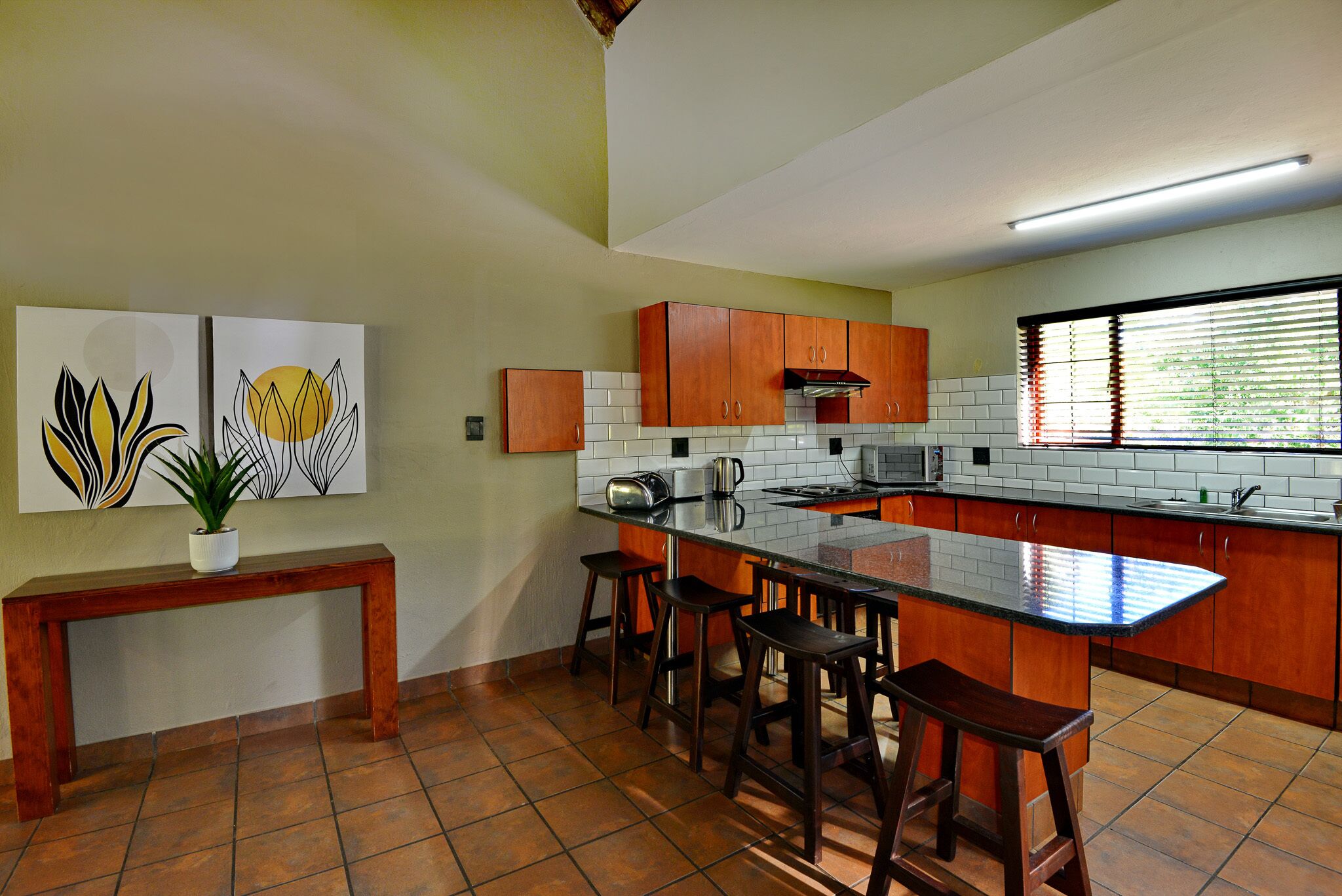 A kitchen with a central island, wooden cabinets, a bench, and a potted plant.