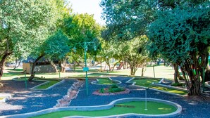 A miniature golf course with a green layout, surrounded by trees and a small building. - Seasons Golf, Leisure & Spa (Hartbeespoort/ Brits)