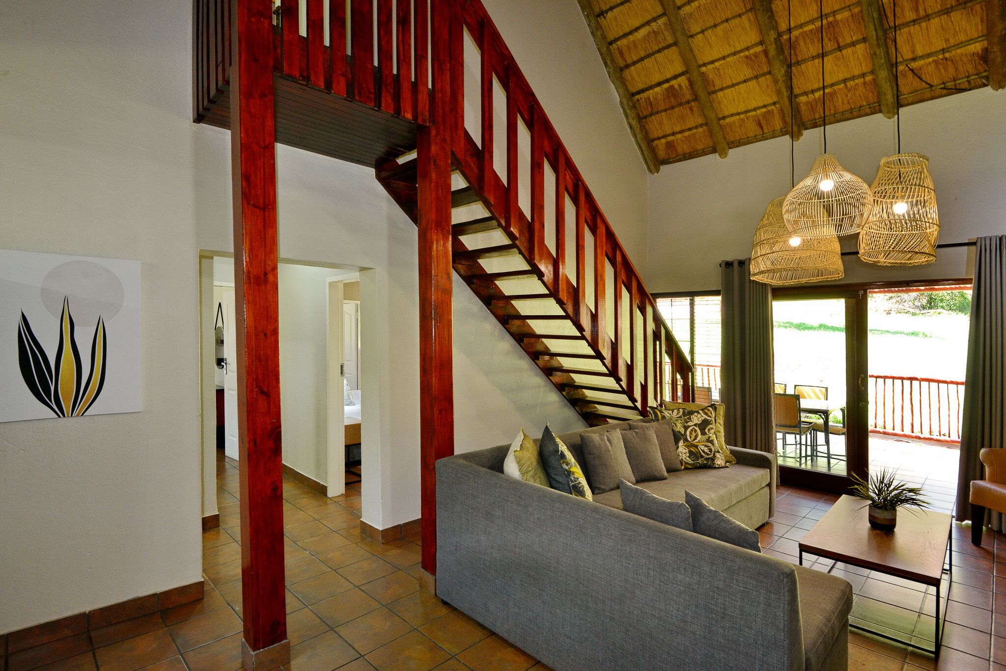 A spacious living area with a staircase, a sofa set, and a dining table.
