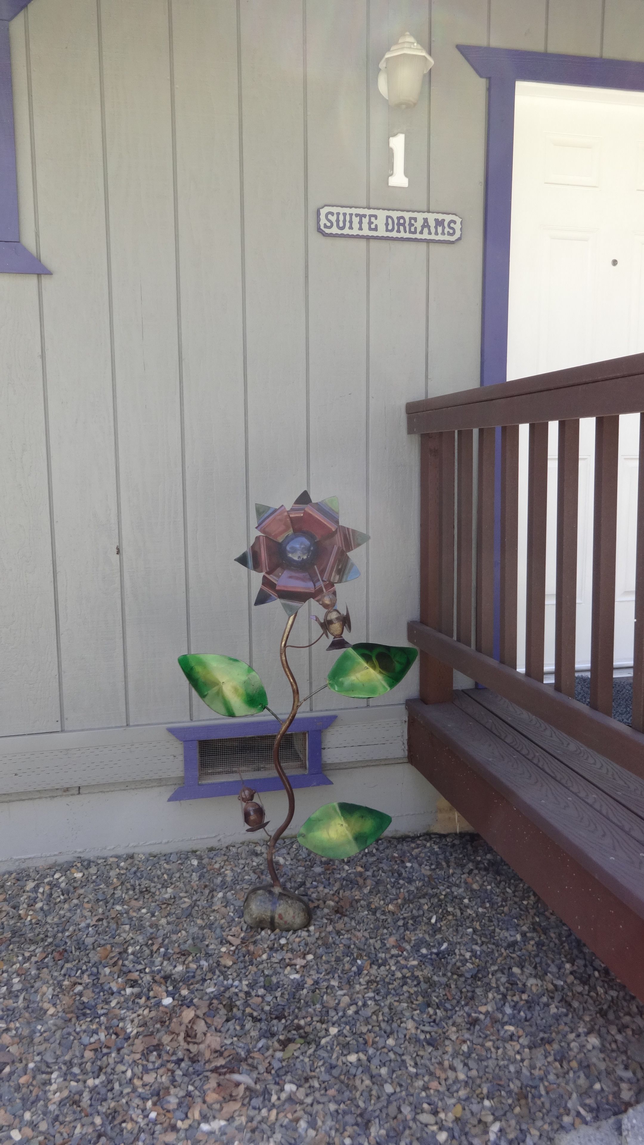 A decorative flower sculpture on a porch with a sign reading "SUITE DREAMS" above it.