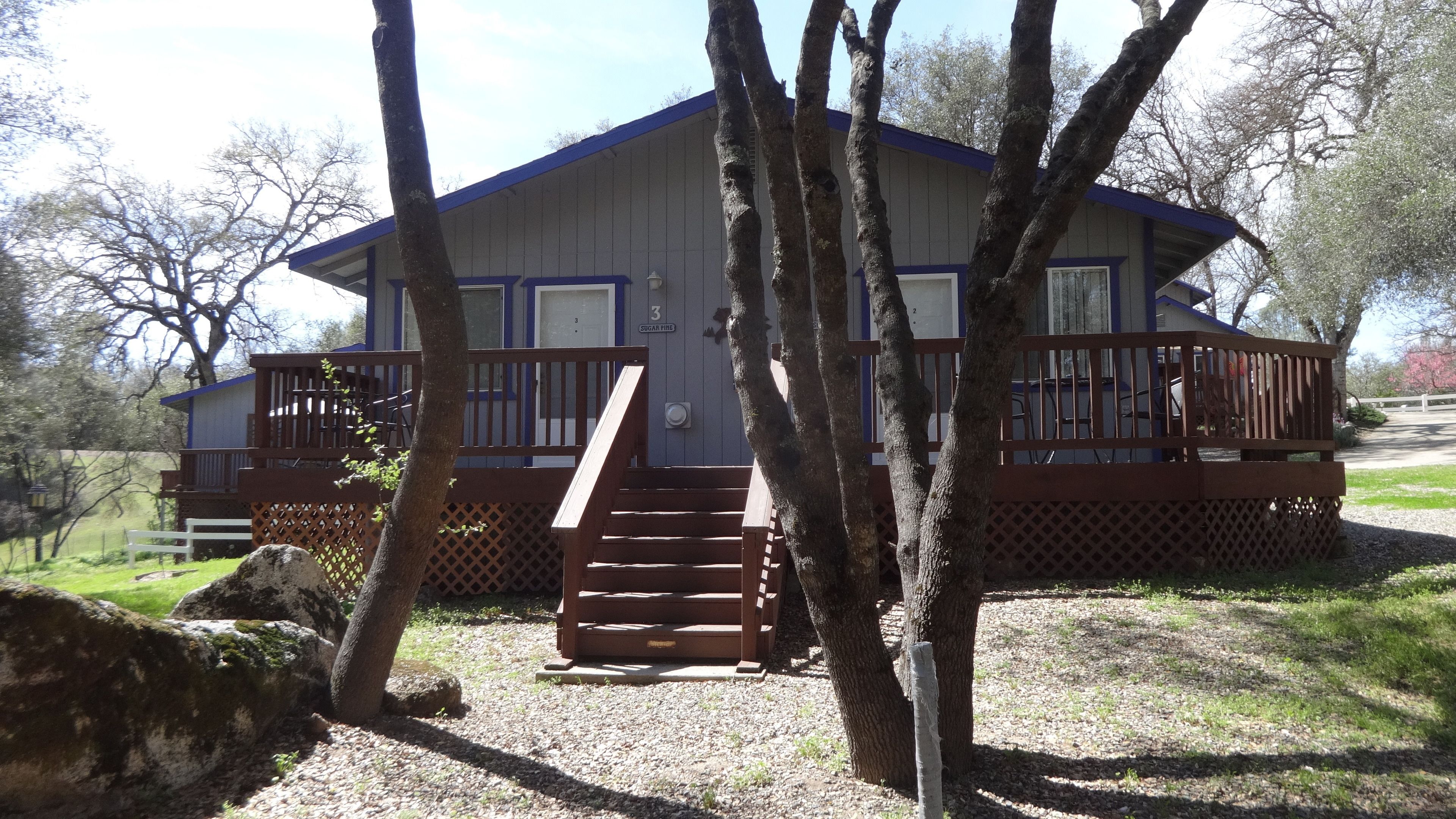 A cabin with a deck, stairs, and a view of the surrounding trees.