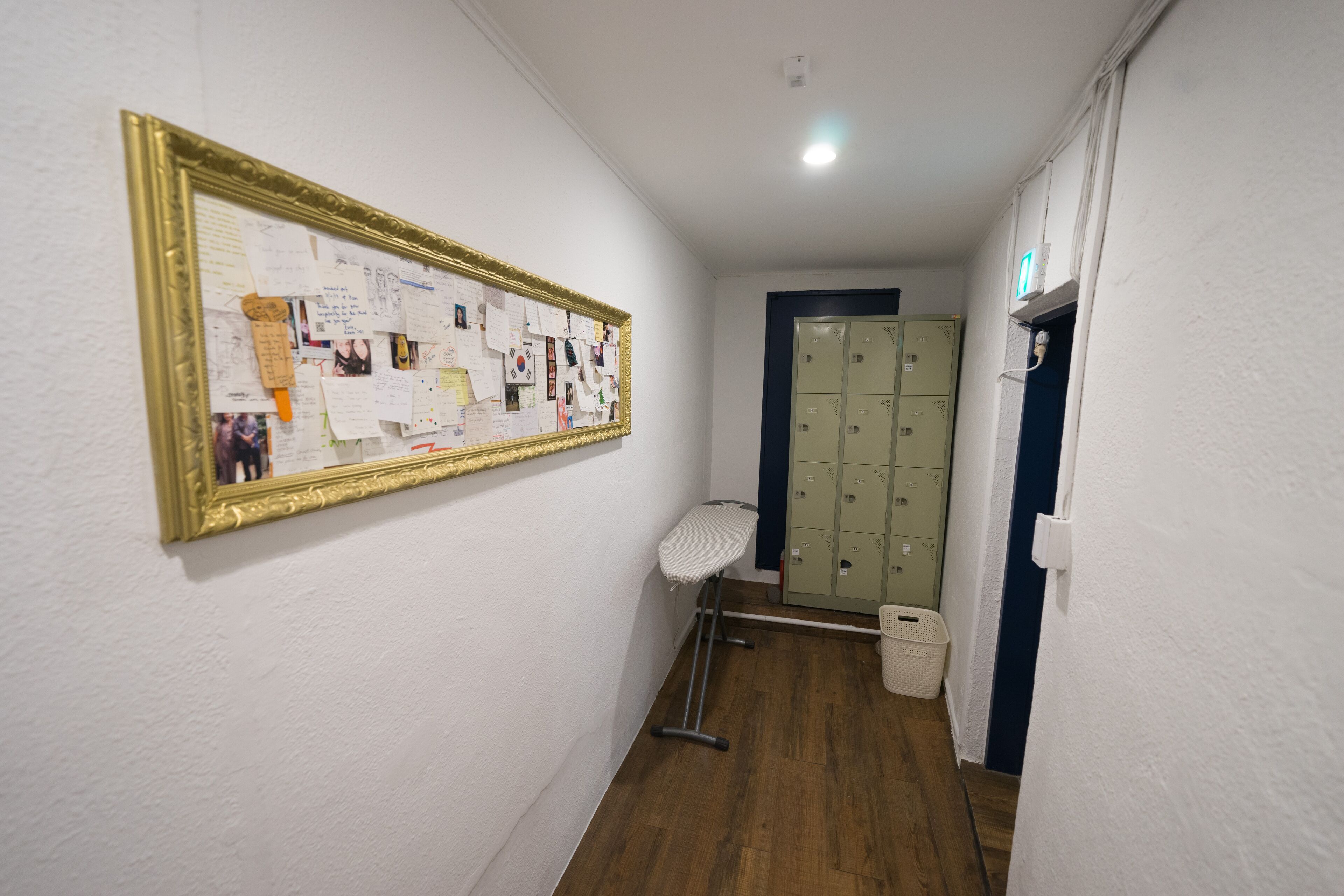 En hall med en anslagstavla, en klädhängare, en papperskorg och ett antal skåp.