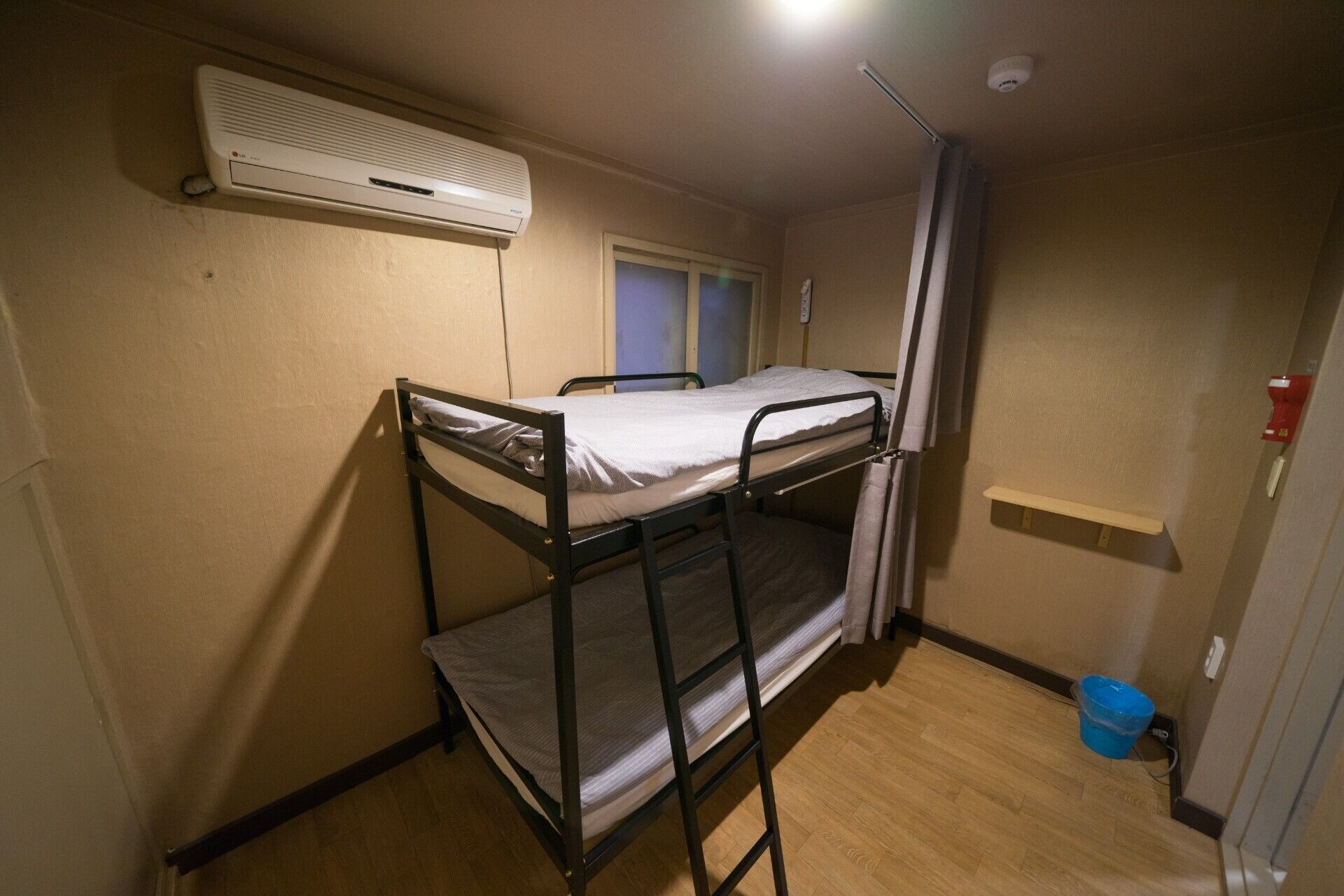 Habitación con literas, una ventana, un calentador y un estante pequeño.