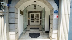 A hotel entrance with a glass door, a doormat, and a sign indicating room number 77-4. - Beewon Guest House - Hostel (Seoul)