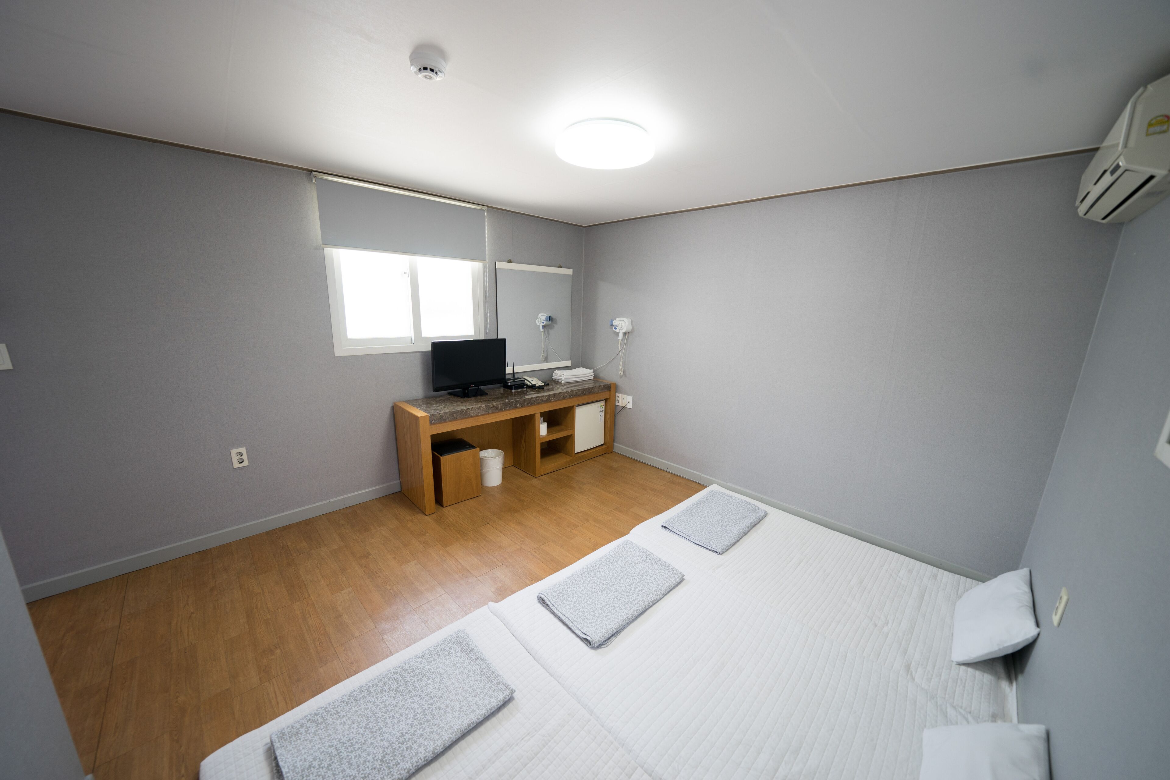 Una stanza con un letto, una scrivania, uno specchio e una finestra.