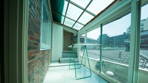 A room with a skylight, a brick wall, and a view of a cityscape. - Beewon Guest House - Hostel (Seoul)