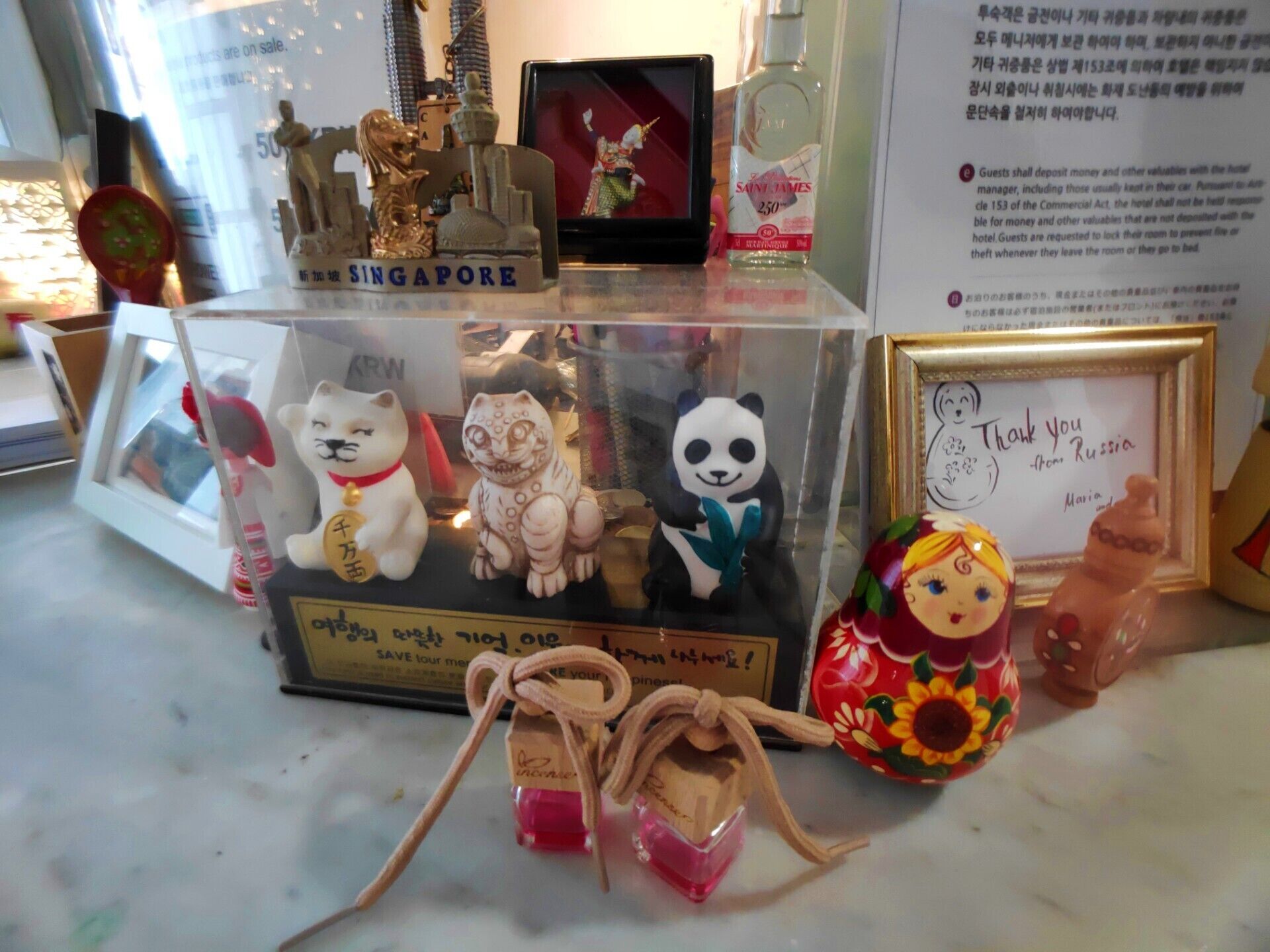 Una exhibición de diversos recuerdos, incluyendo una figurita de gato, un panda y una pequeña botella con tapa roja.