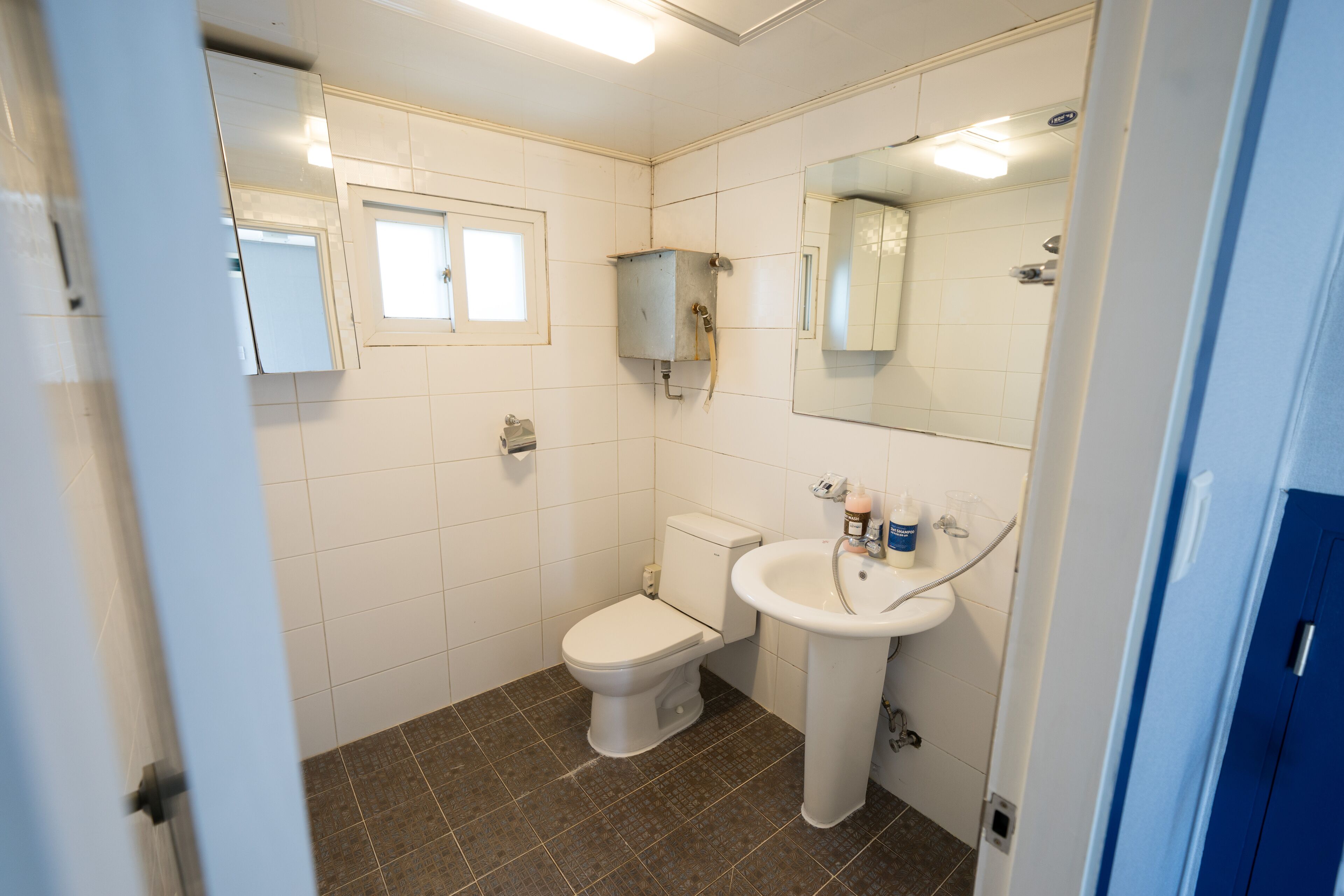 Une petite salle de bain propre, équipée de toilettes, d’un lavabo et d’un miroir.