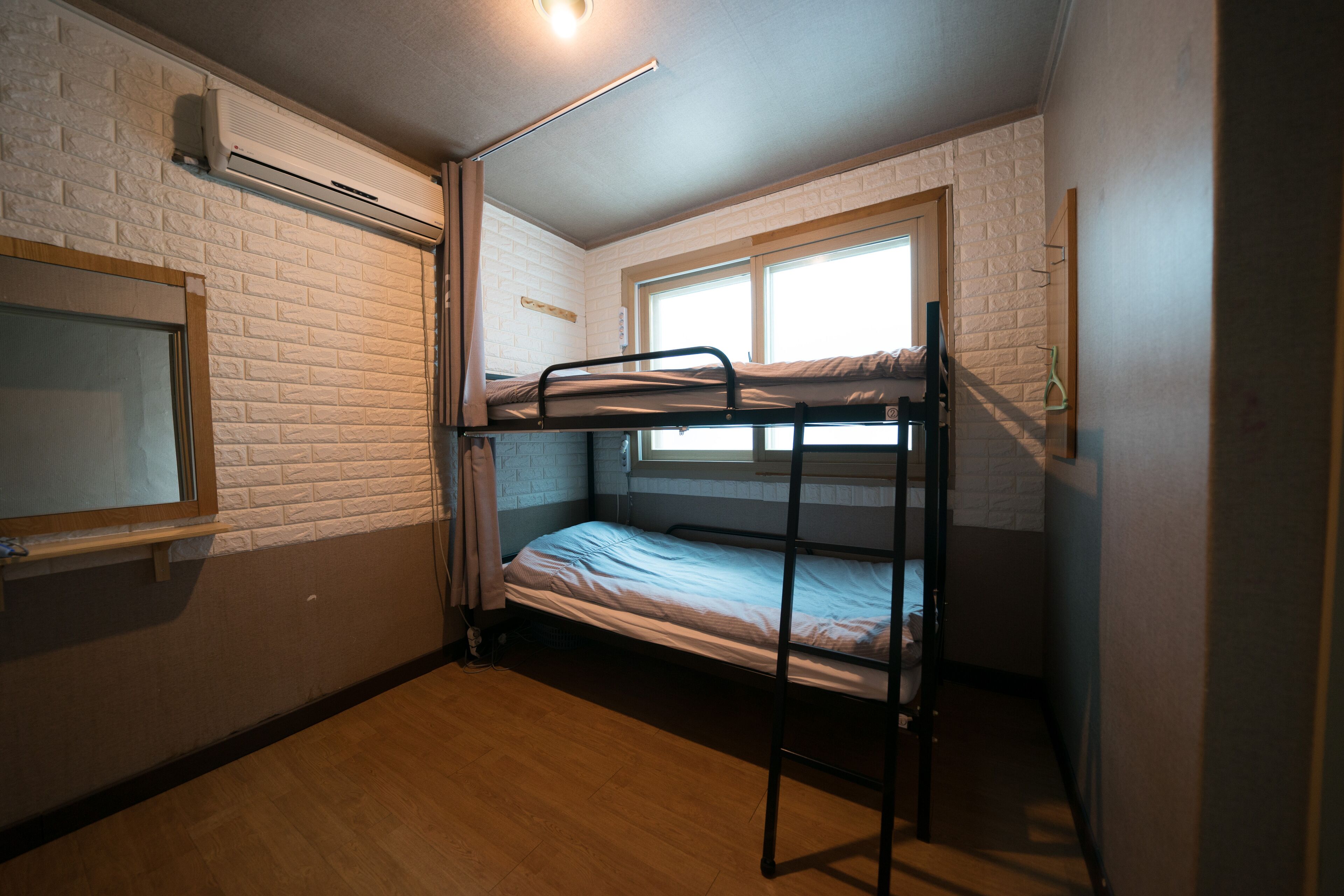 A small, compact room with a bunk bed, a window, and a mirror.