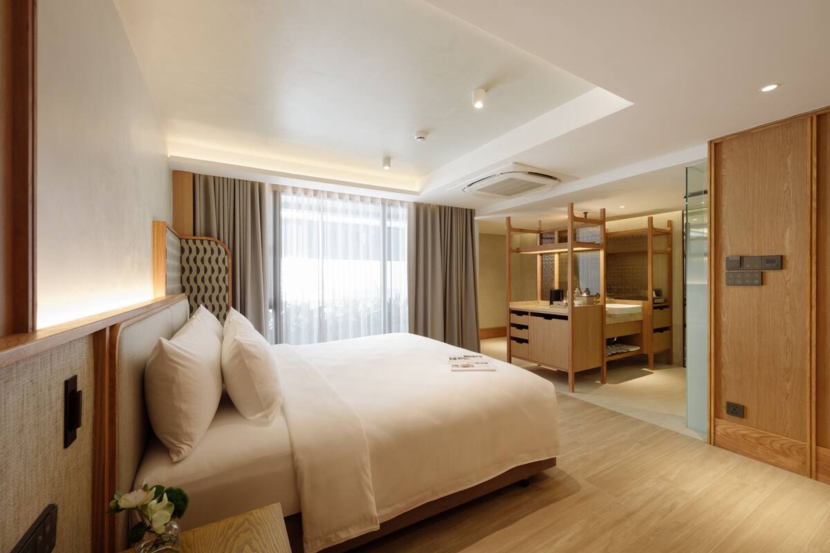 A modern hotel room with a large bed, a desk, and a walk-in closet.