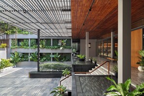 A modern indoor space with a wooden ceiling, a central staircase, and multiple levels with greenery. - Ad Lib Hotel Bangkok (Bangkok)