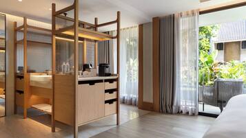 Camera d'albergo moderna con una scrivania in legno, una grande finestra con tende, un letto e vista sul verde circostante.