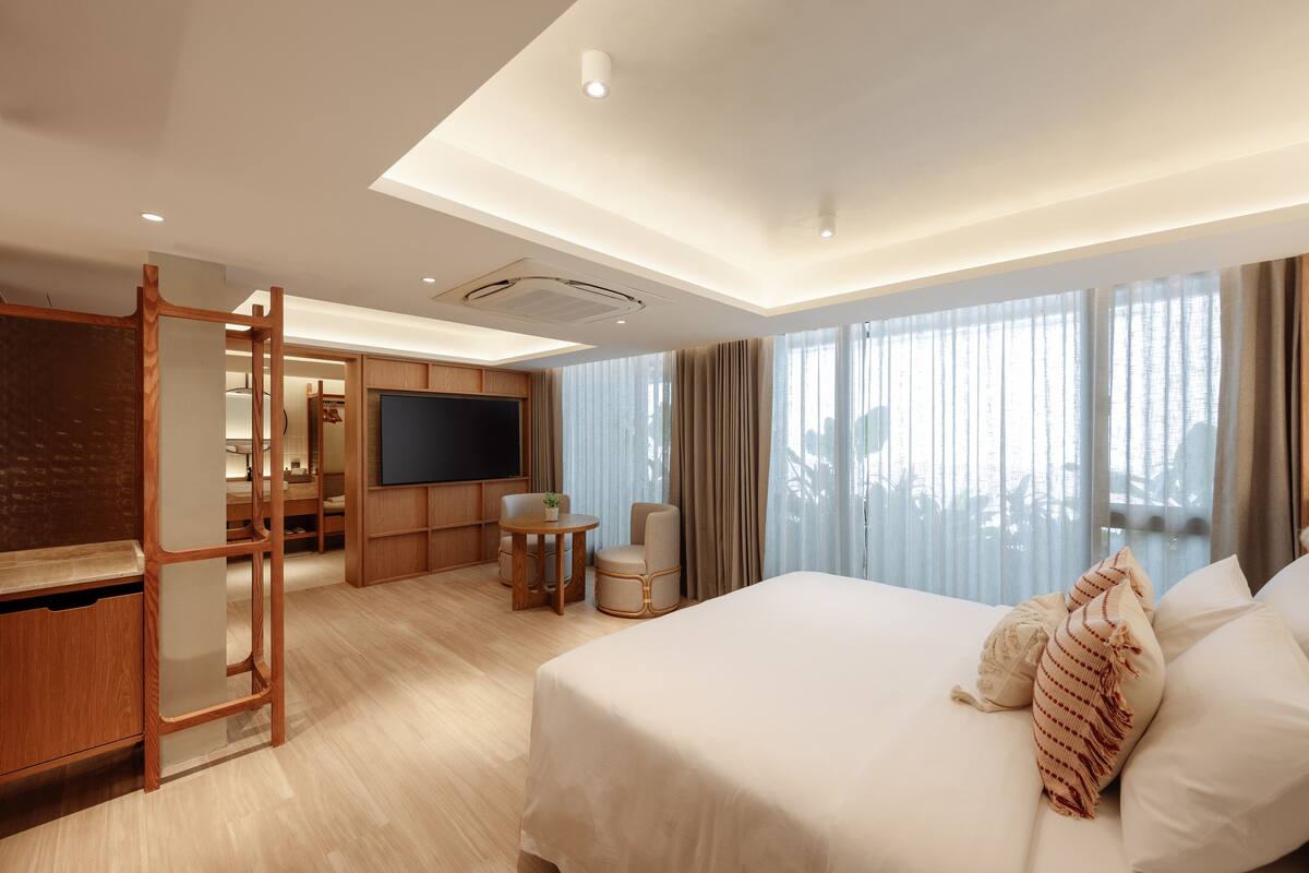 A hotel room with a large bed, a TV, a desk, and a chair.