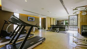 Une salle de sport équipée de tapis de course, d’haltères et d’autres appareils d’exercice.