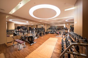 Un gimnasio con equipo de ejercicio, espejos y suelo de madera.