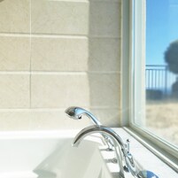 A bathroom with a white sink, chrome faucet, and a window with a view of a balcony.