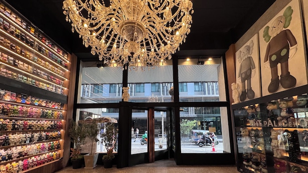 Rebedor d'hotel amb un penjador de cristall, una vitrina amb joguines de peluix i vista al carrer.