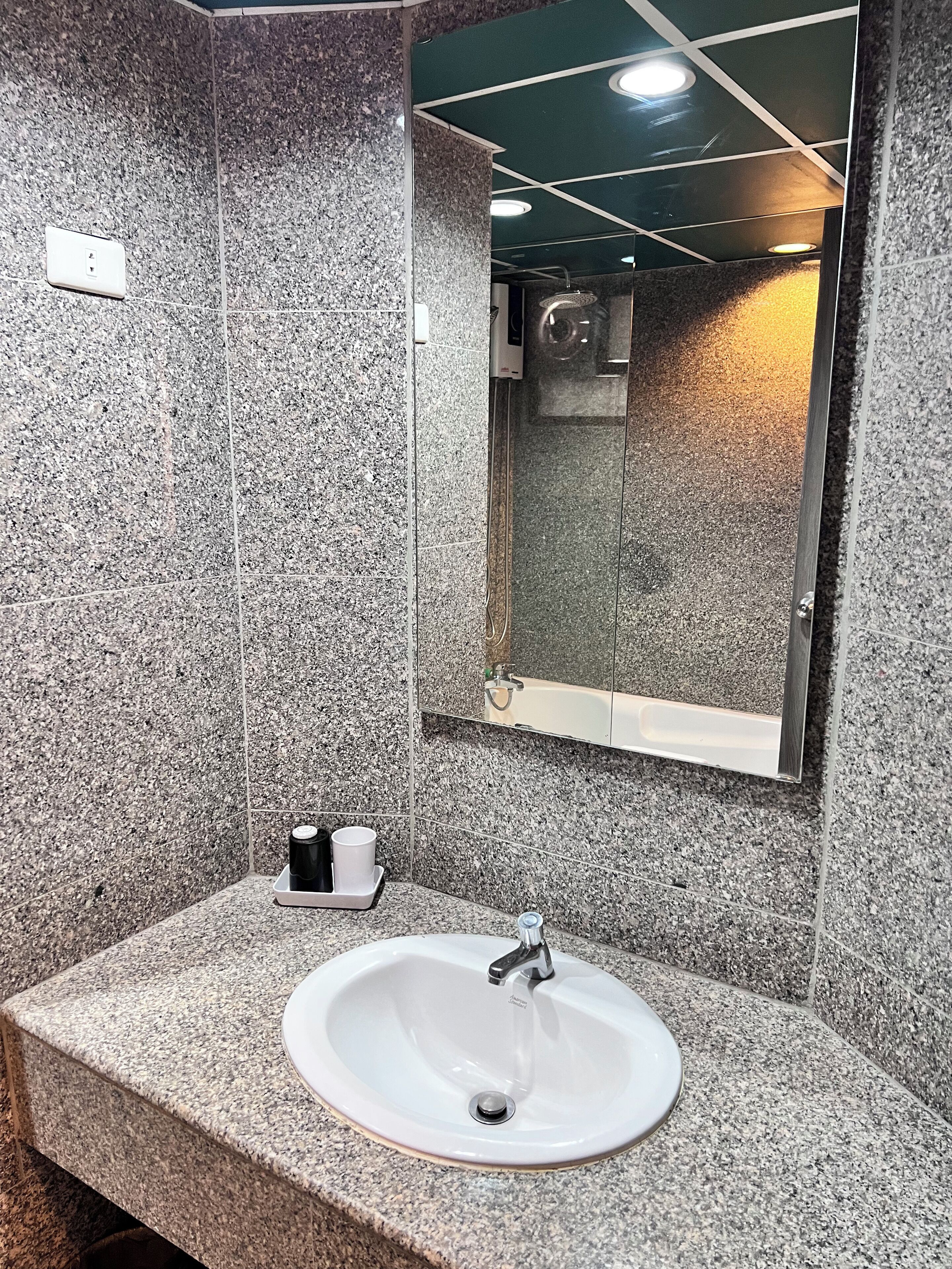 A bathroom with a granite countertop, a white sink, and a mirror.