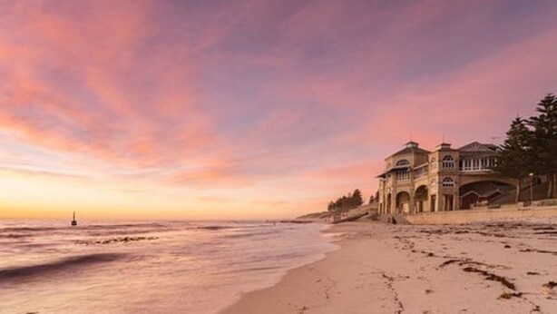 A beachfront hotel with a large building, a sandy beach, and a calm sea. - Cottesloe Beach Chalets (Cottesloe)