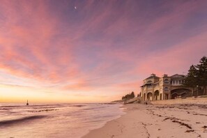 A beachfront hotel with a large building, a sandy beach, and a calm sea. - Cottesloe Beach Chalets (Cottesloe)