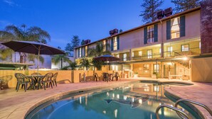 A pool area with a clear pool, outdoor seating, and a building with multiple balconies. - Cottesloe Beach Chalets (Cottesloe)
