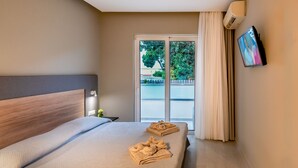 A hotel room with a bed, a TV, and a view of the outdoors. - Sunday Hotel (Rhodes)