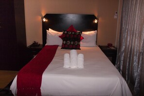 A neatly made bed with white linens, a red throw blanket, and a decorative pillow with a polka dot pattern. - Scenery Guesthouse Stadium (Maseru)