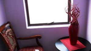 Habitación de esquina con una silla de madera y una mesita con un florero.