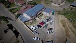 Vista aérea de una zona residencial con un edificio grande de techo plano y varios autos estacionados.