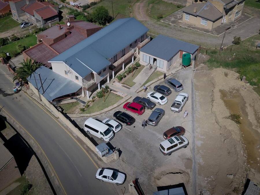 An aerial view of a residential area with a large building featuring a flat roof and multiple parked cars.