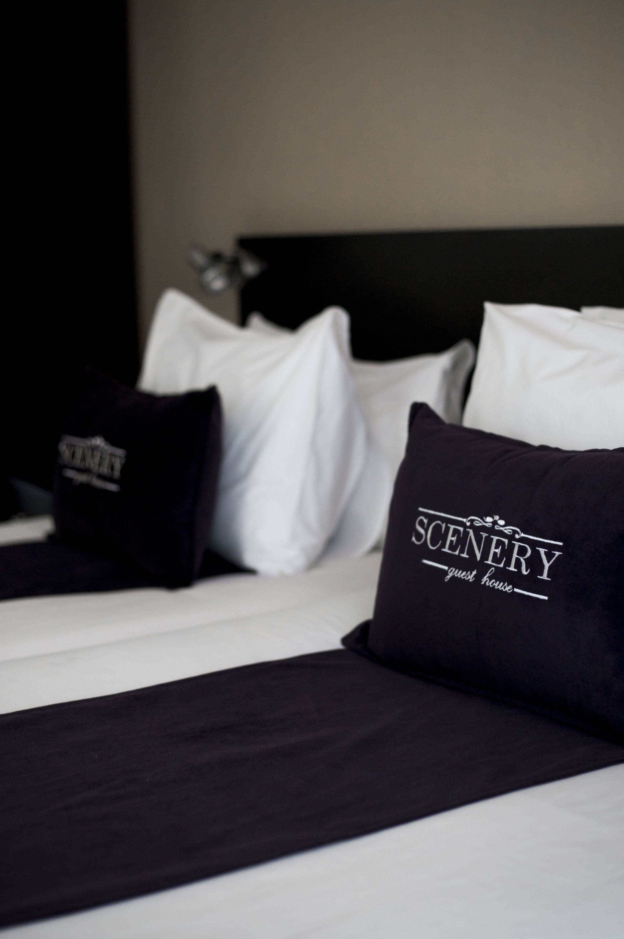 Una cama bien hecha con ropa de cama blanca y negra, incluyendo almohadas con texto.