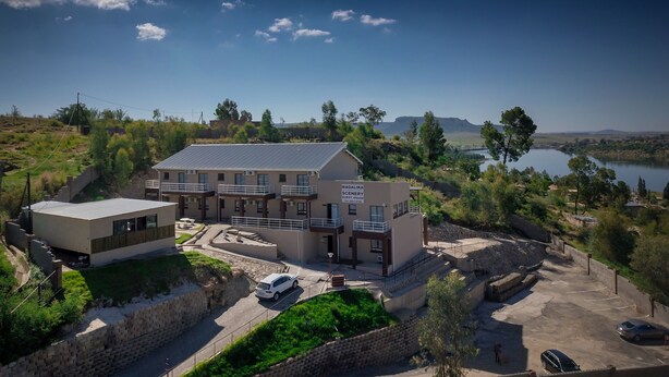 A guest house named "MAQALIKA SCENERY" with a view of a lake and hills.