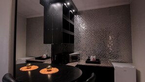 A modern kitchen with a black dining table, chairs, and a microwave.