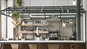 A bar area with shelves of bottles, a coffee machine, and hanging plants. - The Hat Madrid (Madrid)