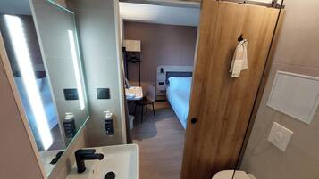 Un bagno moderno con un lavandino in vetro, un water e una porta in legno.