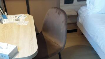 A compact room with a bed, a table, and a chair.