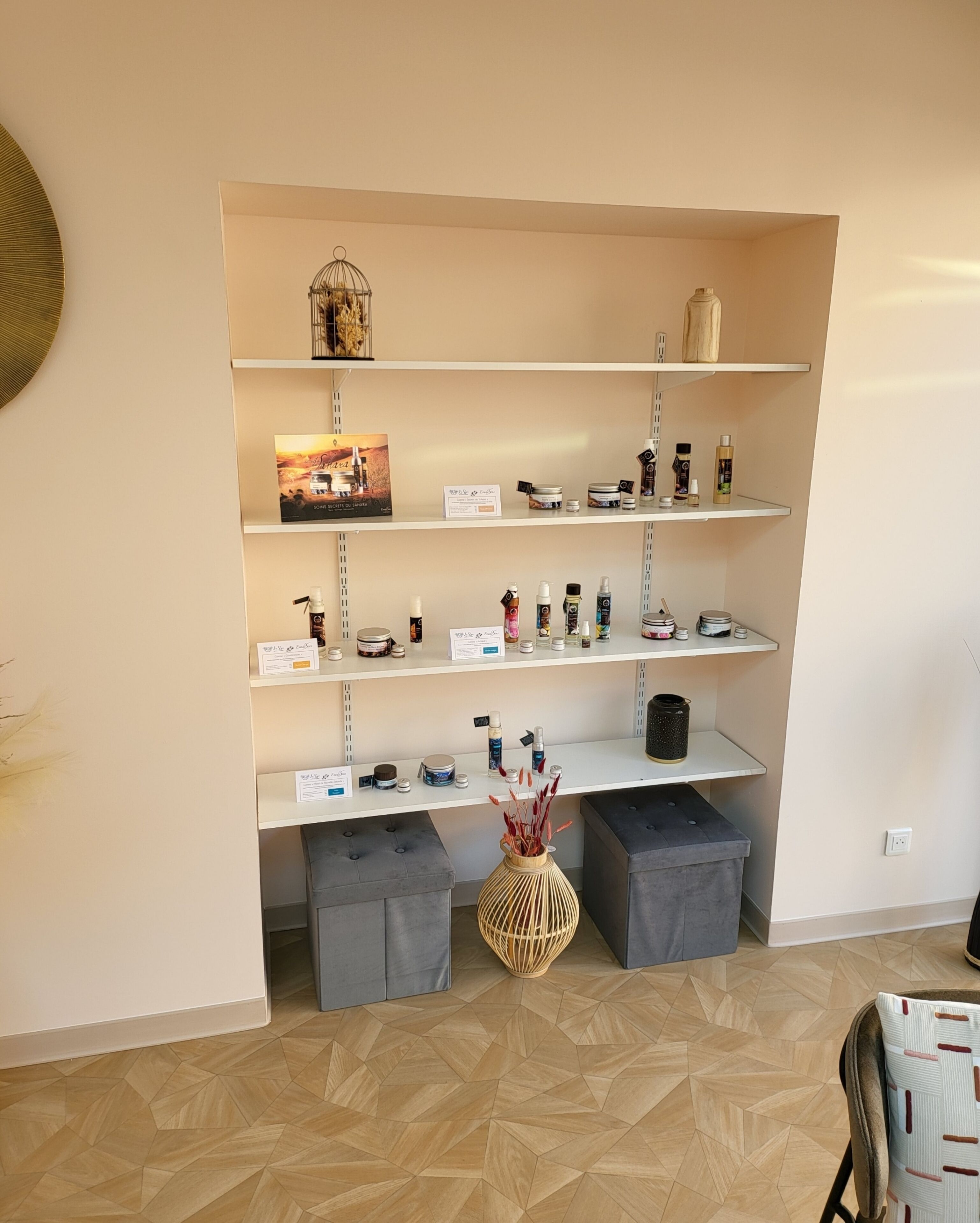 A reception area with a white reception desk, a large woven vase, grey upholstered benches, and a wall-mounted shelf with various items.