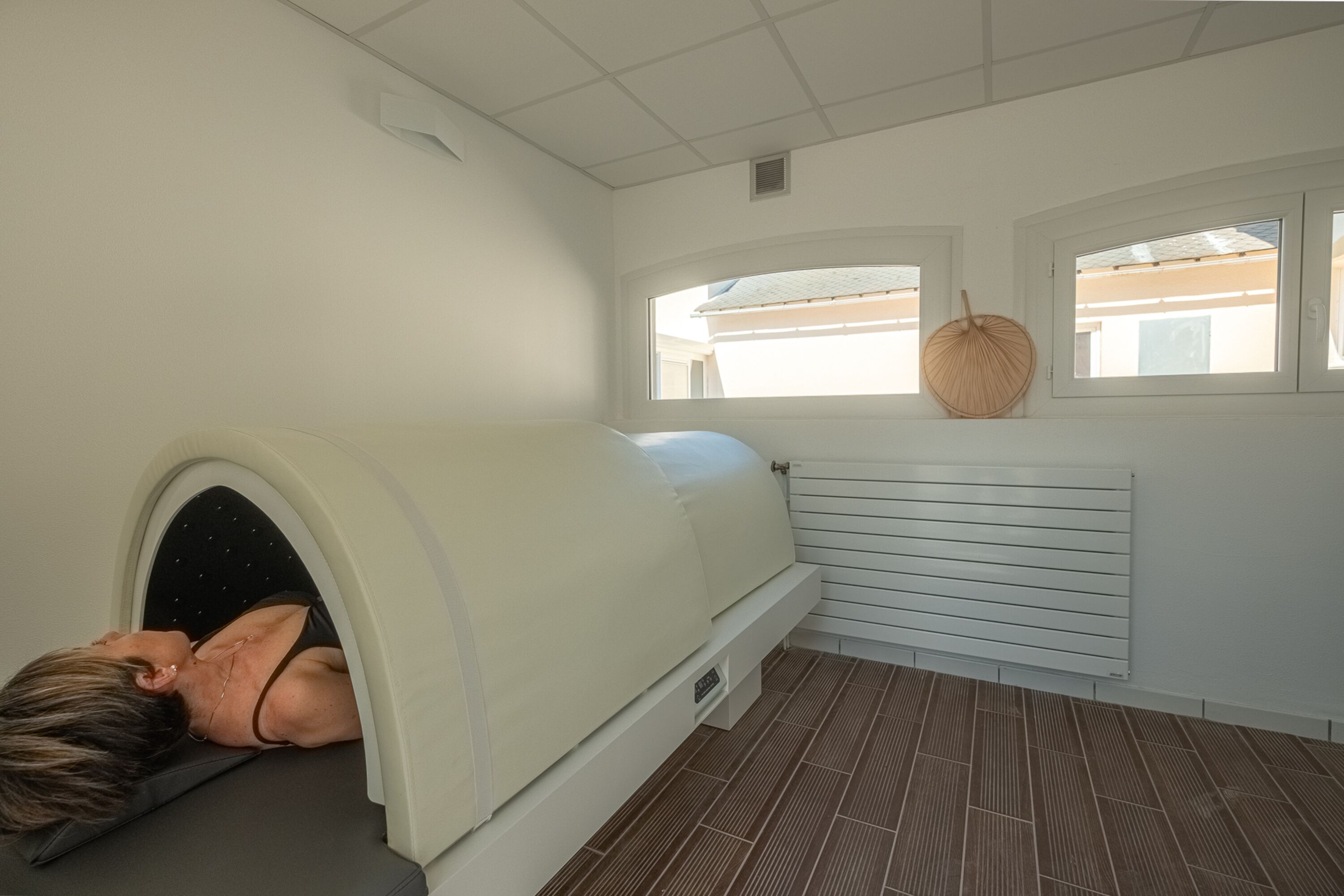 A room with a massage chair, a window with a woven basket, and a radiator.