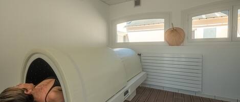 A room with a massage chair, a window with a woven basket, and a radiator.