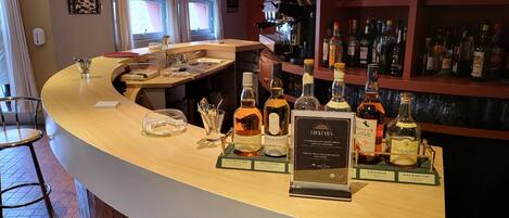 A bar area with a counter displaying various liquor bottles, a coffee machine, and a sign indicating cocktails.