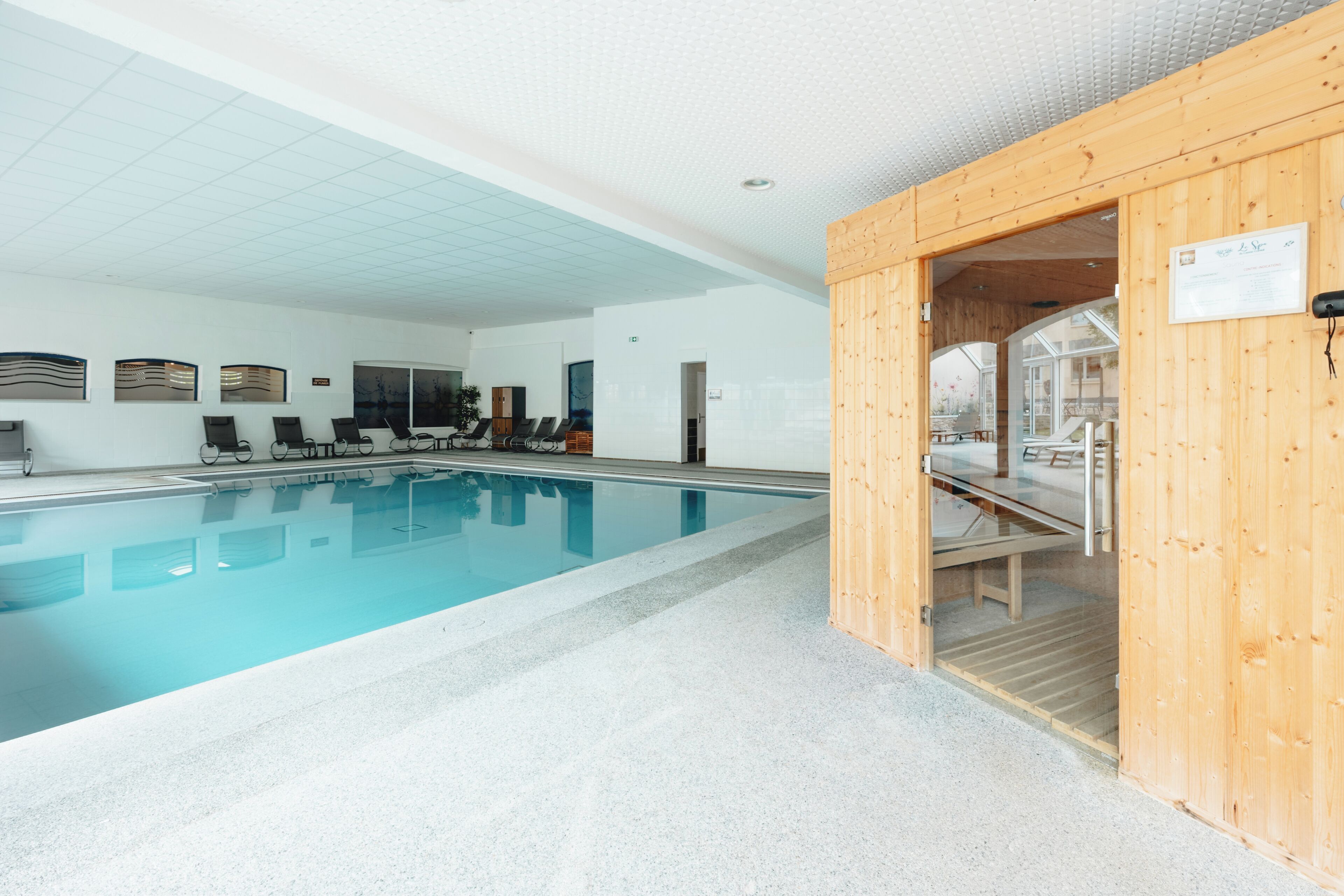 Una piscina con sillas de descanso y un área de sauna.