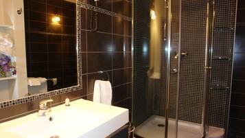 Une salle de bain moderne avec un lavabo blanc, une douche à parois de verre et un grand miroir.