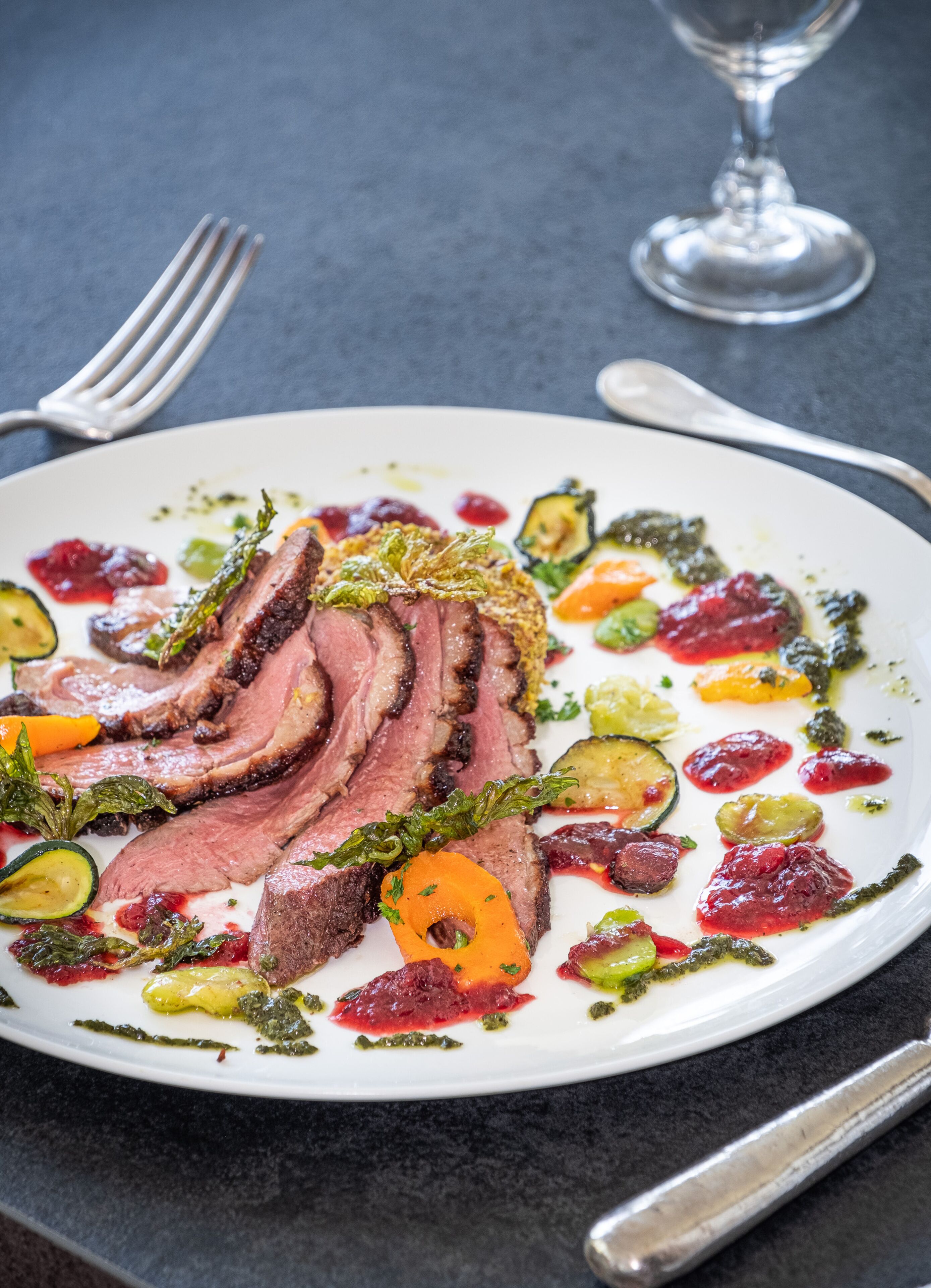 Un plato de carne en rodajas con verduras y salsas.