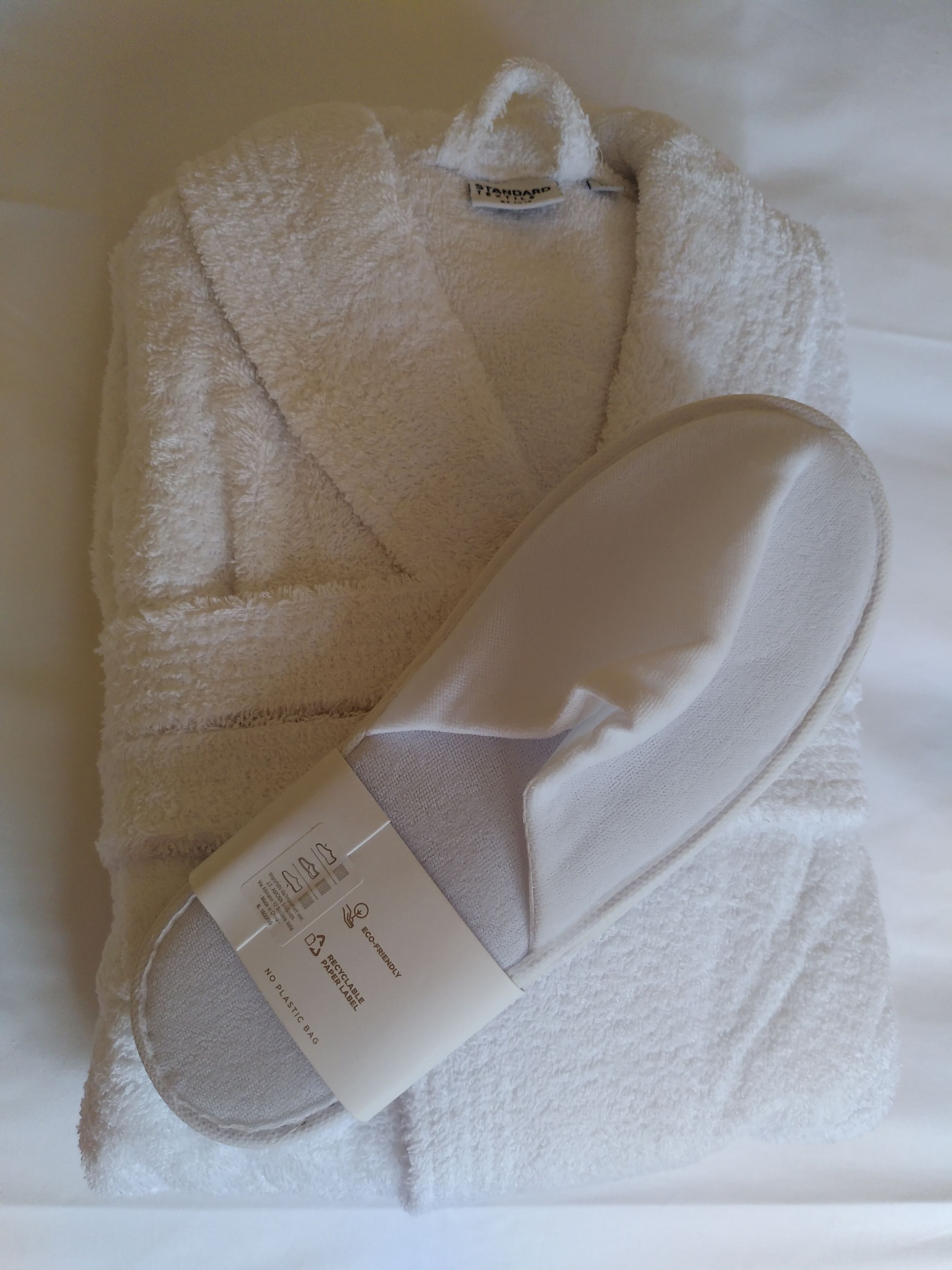Un peignoir blanc et des chaussons sur un lit.