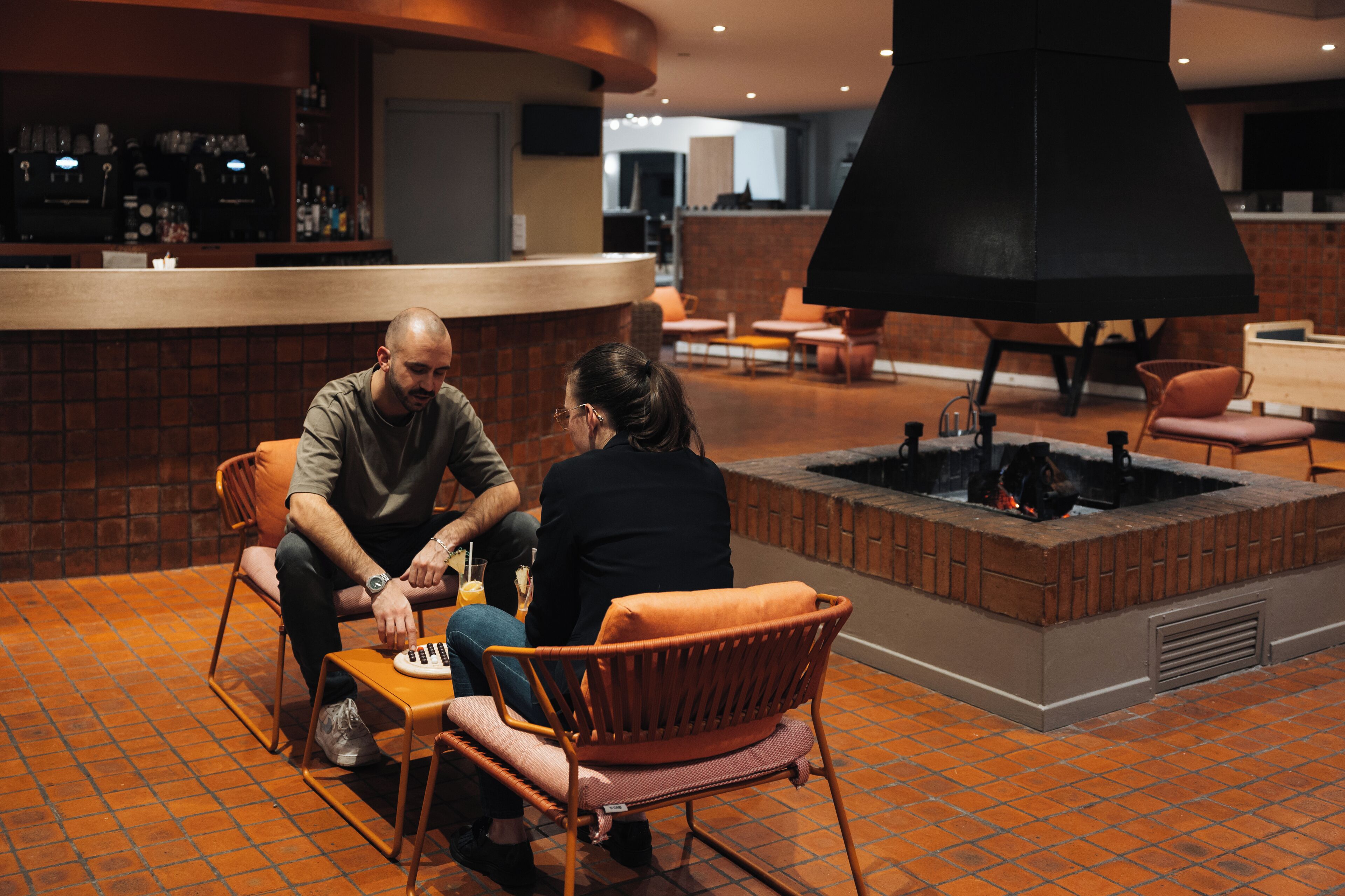 A bar area with a brick fireplace, seating, and a counter with bar equipment.