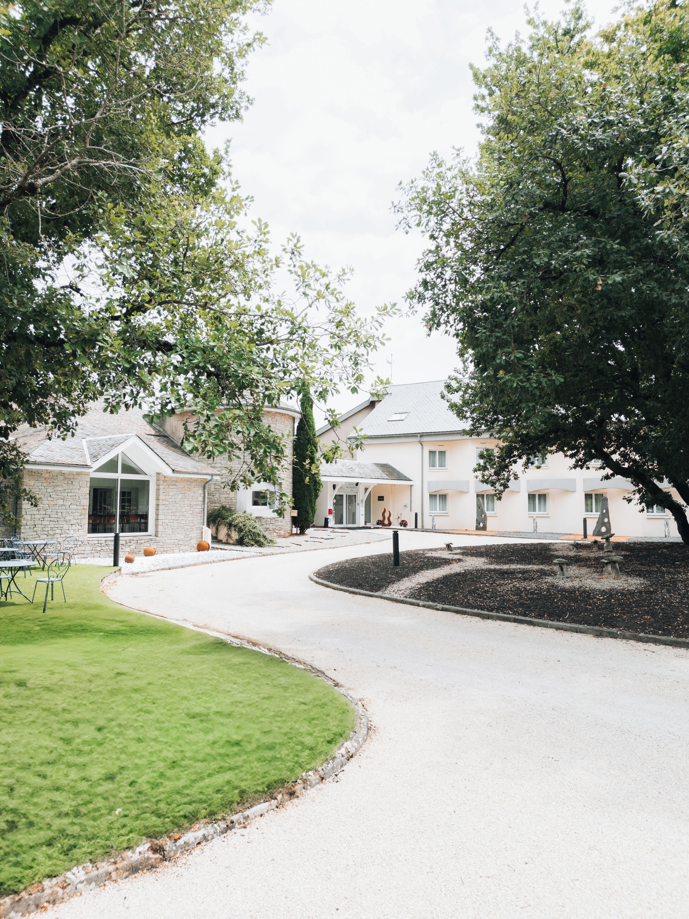 A residential property with a curved driveway, a stone wall, and a well-maintained lawn.