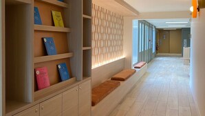 A hallway with built-in shelving units, a patterned wall, and a tiled floor. - Green Hôtels Poitiers (Poitiers)