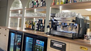 A bar area with a FUTURMAT espresso machine, shelves with bottles and glasses, and two refrigerators. - Green Hôtels Poitiers (Poitiers)