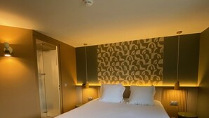 A large bed with white linens, a patterned wall, and two bedside lamps. - Green Hôtels Poitiers (Poitiers)
